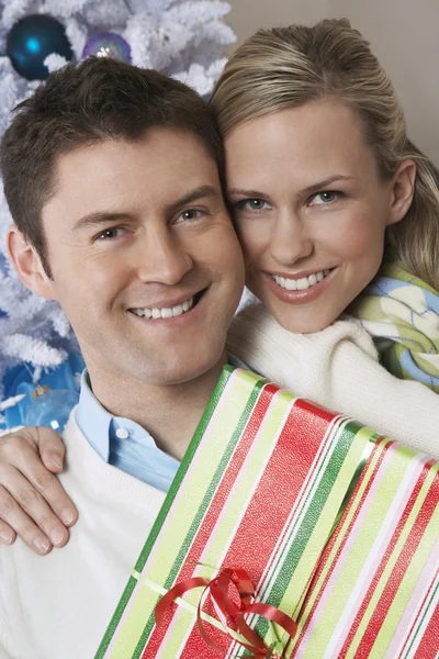 Couple Holding Present By Christmas Tree — Stock Photo, Image