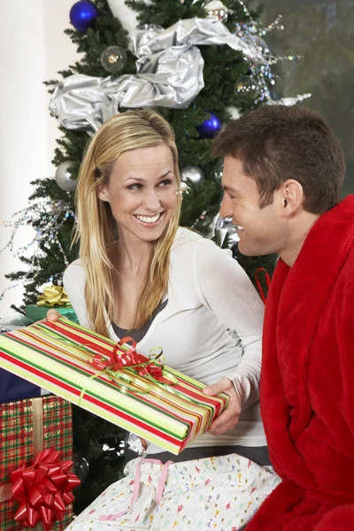 Par med nuvarande sitter av julgran — Stockfoto