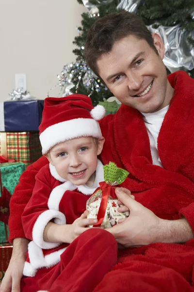 Retrato de padre e hijo en traje de Papá Noel sosteniendo presente — Foto de Stock