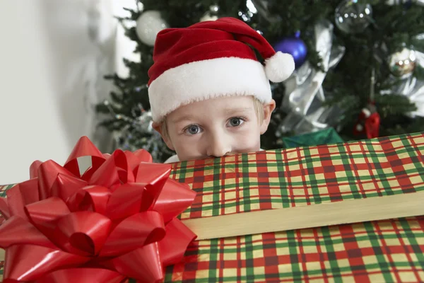 Niño en Santa Sombrero asomándose a la caja de regalo — Foto de Stock