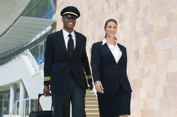 Pilot und Flugbegleiterin gehen vor Gebäude — Stockfoto