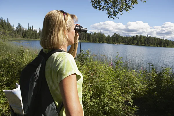 Kvinna med kikare på sjön — Stockfoto