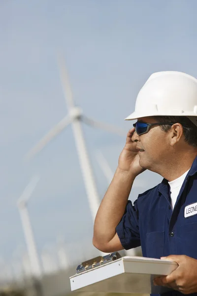 Инженер с помощью мобильного телефона на ветряной электростанции — стоковое фото