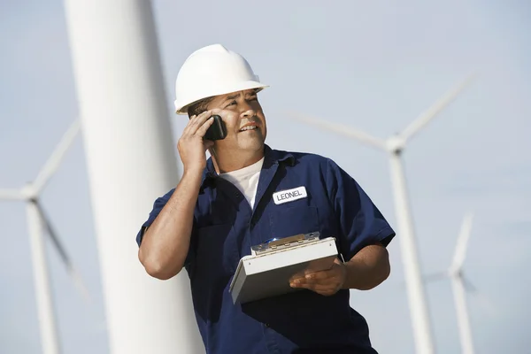 Инженер с помощью мобильного телефона на ветряной ферме — стоковое фото