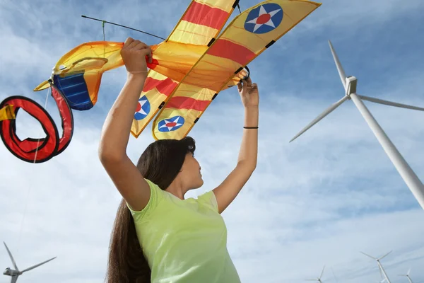 Niña sosteniendo avión cometa en parque eólico — Foto de Stock