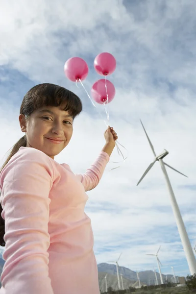 Menina segurando balões na fazenda eólica — Fotografia de Stock