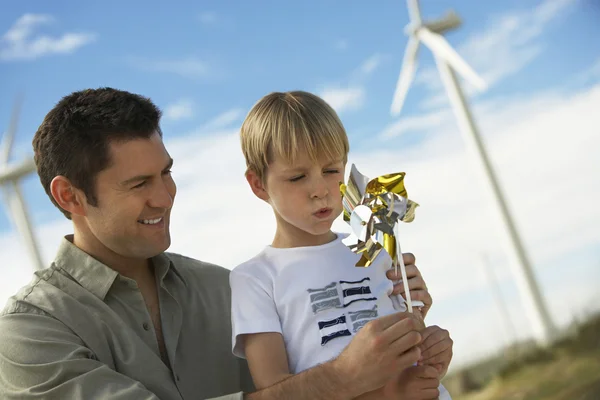 Chico soplando juguete molino de viento con padre — Foto de Stock
