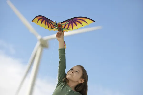 Девушка играет с воздушным змеем на ветряной ферме — стоковое фото