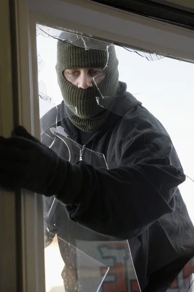 Maskovaný zloděj vloupání oknem — Stock fotografie