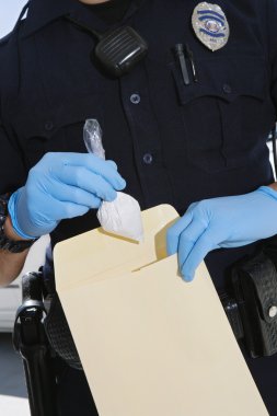 Polis memuru kokain kanıt zarfa koyarak