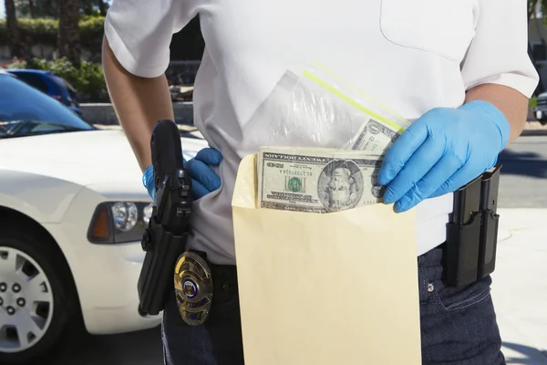 Un policier met de l'argent dans une enveloppe de preuves — Photo