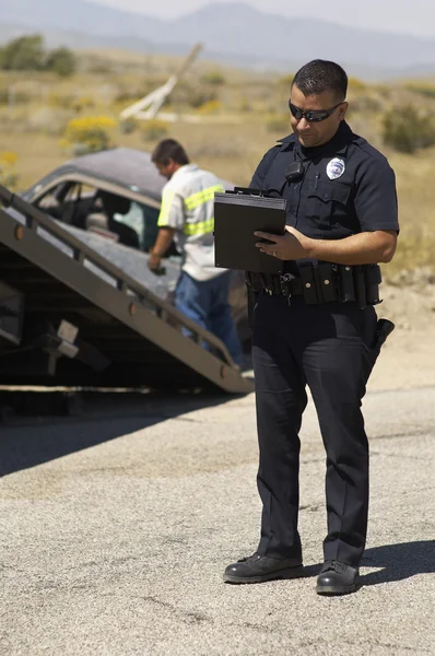 Офицер полиции пишет заметки на месте аварии — стоковое фото