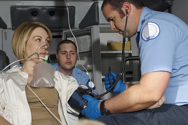 Paramédicos cuidando da vítima em ambulância — Fotografia de Stock