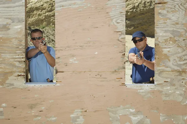 Two Men Aiming Hand Guns At Firing Range