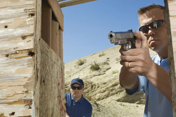 Человек, наблюдающий за коллегой по стрельбе из ручного пистолета — стоковое фото