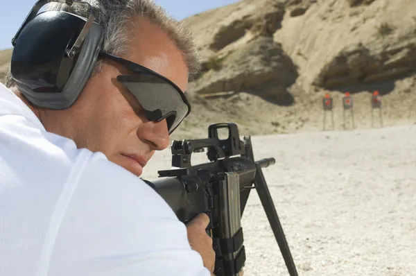 Hombre apuntando ametralladora en campo de tiro — Foto de Stock