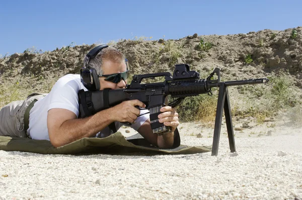 Uomo che punta mitragliatrice al poligono di tiro — Foto Stock