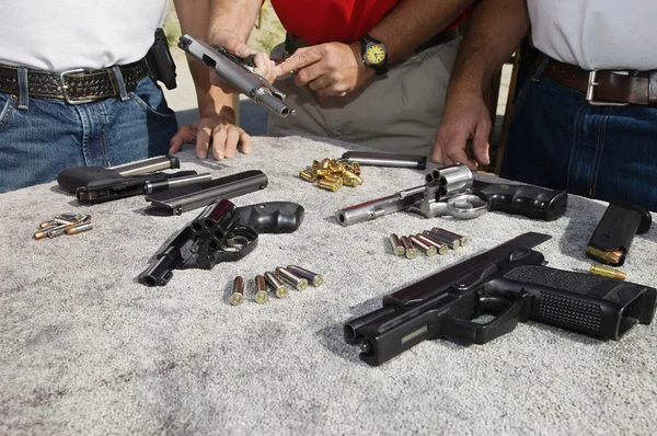 Drie mannen met pistolen op tafel — Stockfoto
