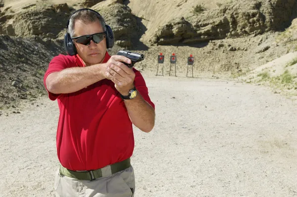 Hombre apuntando pistola de mano en el campo de tiro —  Fotos de Stock