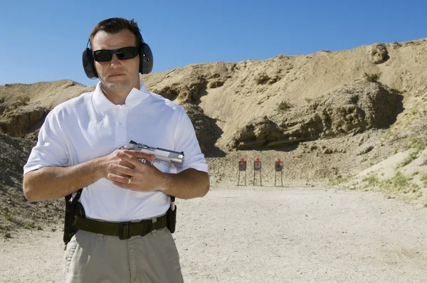 Hombre sosteniendo pistola de mano en el campo de tiro — Foto de Stock