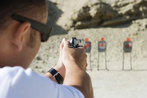 Uomo che punta la pistola a mano al poligono — Foto Stock