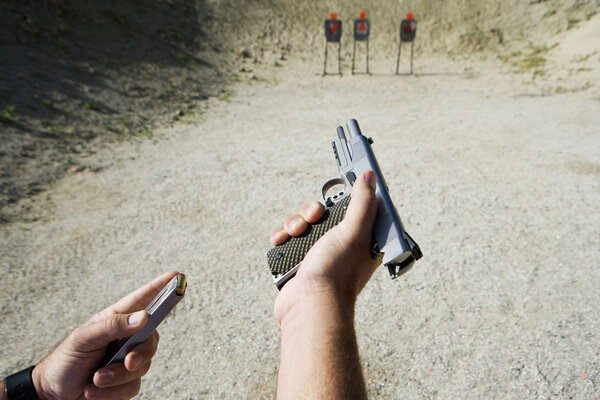 Man 's Hands Loading Gun At Fire Range
