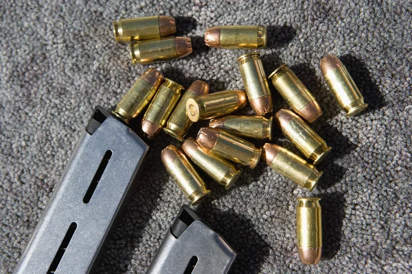 Zbraň, zásobník a náboje na koberci — Stock fotografie