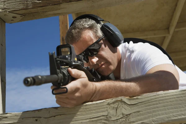 Homem apontando metralhadora em alcance de fogo — Fotografia de Stock
