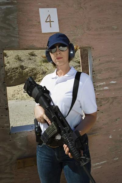 Mujer sosteniendo ametralladora en el campo de tiro — Foto de Stock