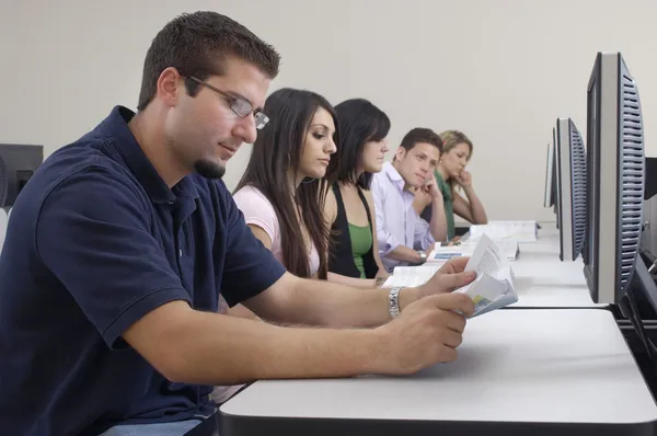 Estudiantes estudiando mientras están sentados en el laboratorio de computación —  Fotos de Stock