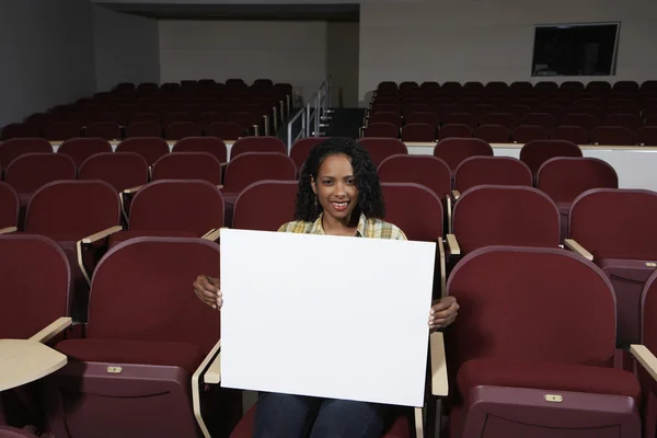 Kvinnlig student med tecken styrelse i klassrummet — Stockfoto