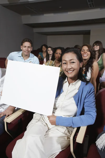 Вчитель тримає білборд зі студентами на задньому плані — стокове фото
