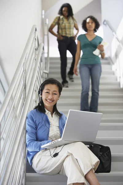 Professor met behulp van laptop terwijl studenten lopend onderaan de trap — Stockfoto