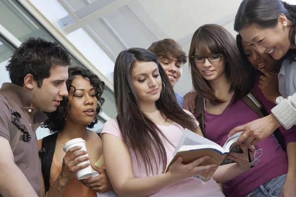 Estudiantes leyendo libro con profesor — Foto de Stock