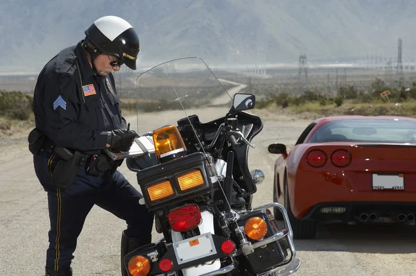 Traffic Cop Writing Against Motorcycle Stock Image