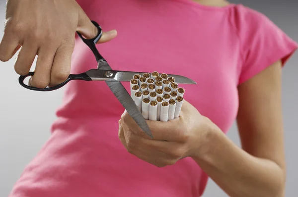 Mulher que corta o pacote de cigarros — Fotografia de Stock