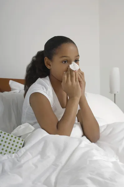 Chica soplando nariz en la cama — Foto de Stock