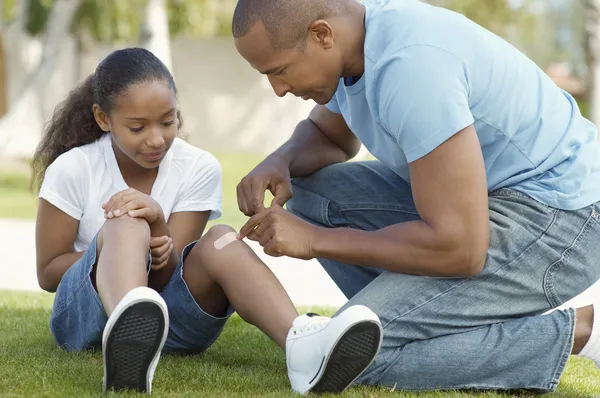 Vater klebte im Park Binde am Knie der Tochter — Stockfoto