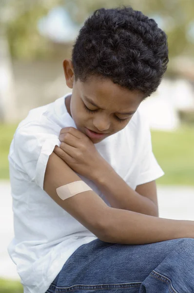 Pojken tittar på bandage på arm — Stockfoto