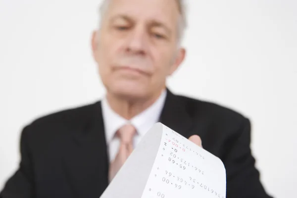 Бизнесмен смотрит на калькуляторную бумагу — стоковое фото