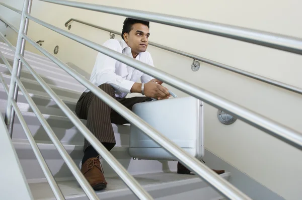 Молодой бизнесмен, сидящий на лестнице — стоковое фото