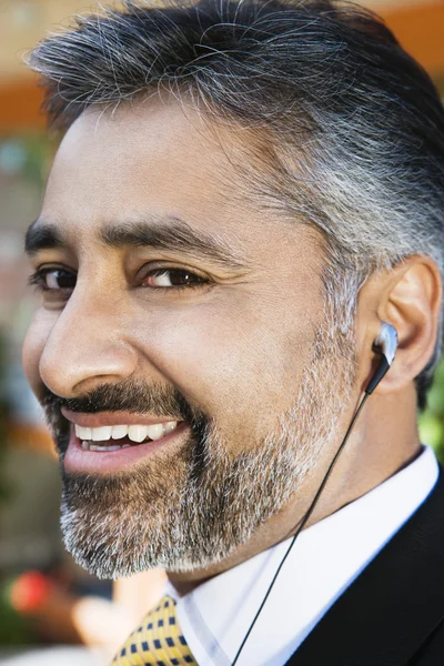 Empresario escuchando música a través de auriculares —  Fotos de Stock