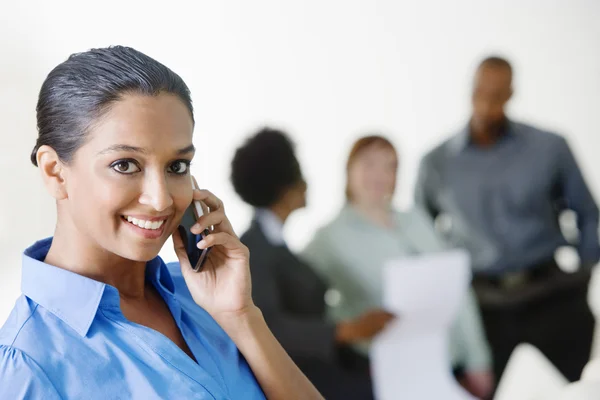 Businesswoman On Call With Colleagues Discussing In The Background — Stock Photo, Image