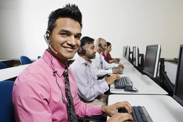 Jonge klant dienst operator met collega's op kantoor — Stockfoto