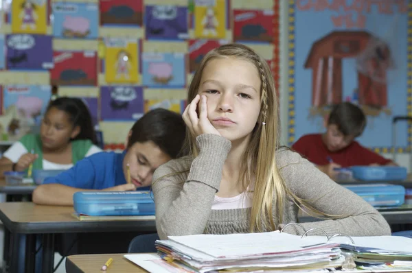 Mädchen langweilt sich, während Mitschüler im Hintergrund Notizen schreiben — Stockfoto