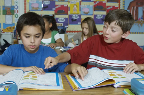 Pupils in classroom reading textbooks — Stock Photo, Image