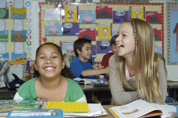 Vrouwelijke vrienden lachen in de klas — Stockfoto