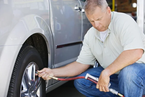 Mechaniker pumpt Reifen auf — Stockfoto