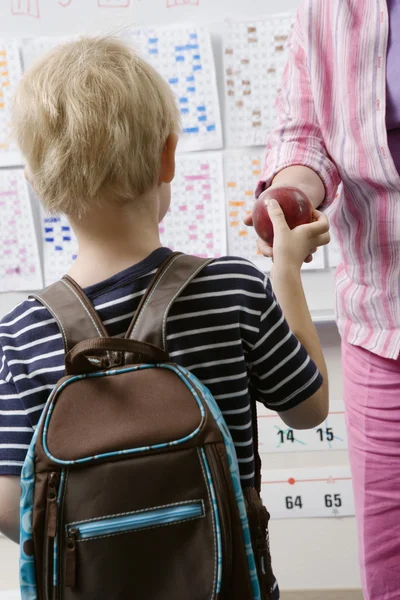 Liten pojke lämnar läraren ett äpple — Stockfoto