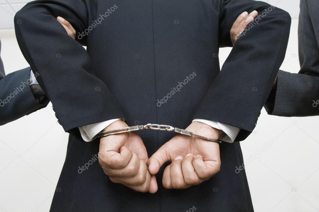 Businessman With Handcuffs While Partners Holding His Arms